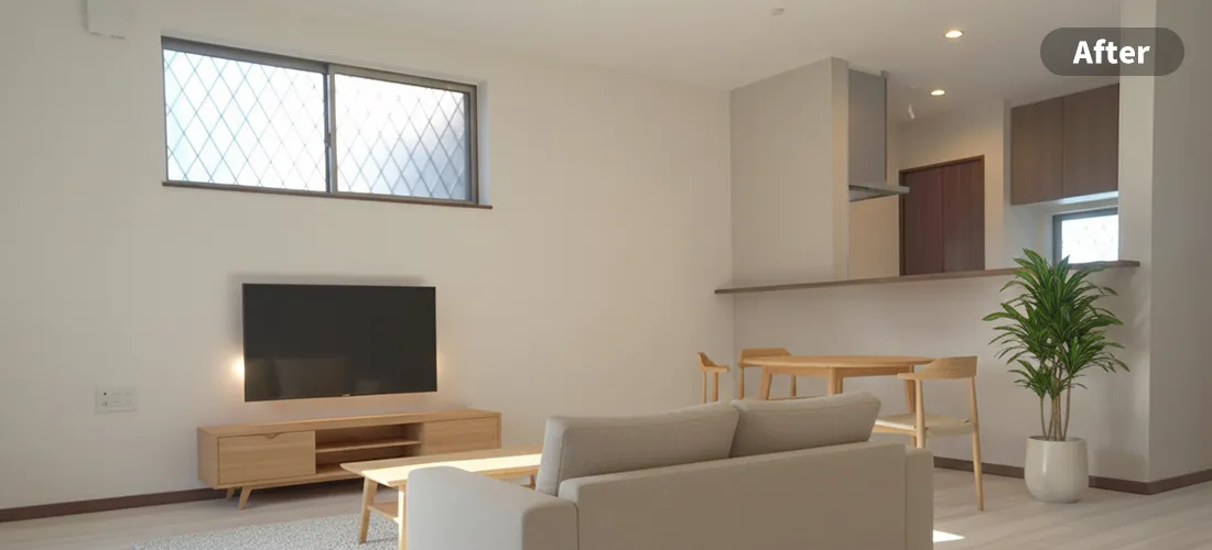 リビングのステージングアフター画像　手前に木製の丸テーブルと四客の椅子、奥にベージュのソファと木製のローチェスト、壁掛けのモニター、白い鉢の大きな観葉植物が置かれている